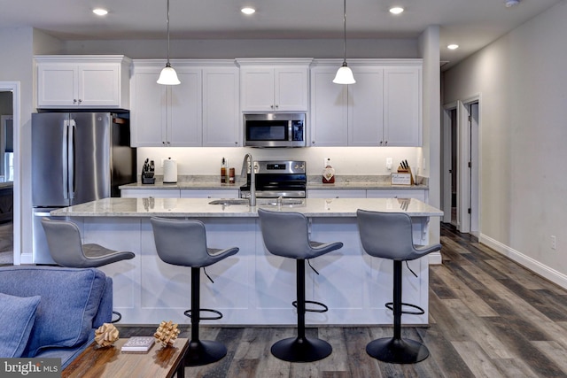 kitchen featuring a sink, an island with sink, stainless steel appliances, white cabinetry, and dark wood-style flooring