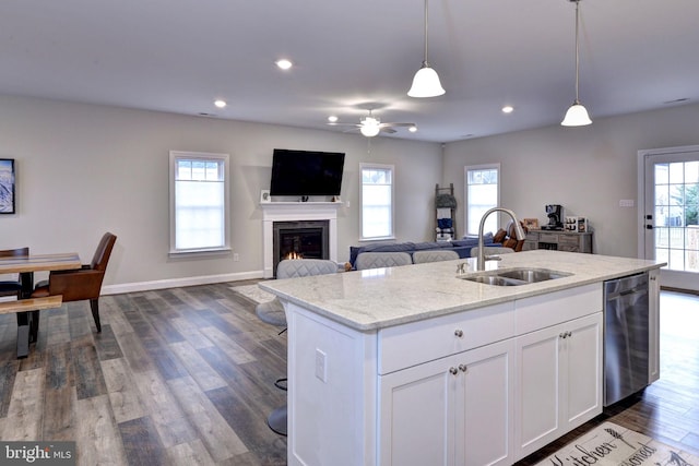 kitchen featuring dark wood-type flooring, a center island with sink, a sink, decorative light fixtures, and dishwasher