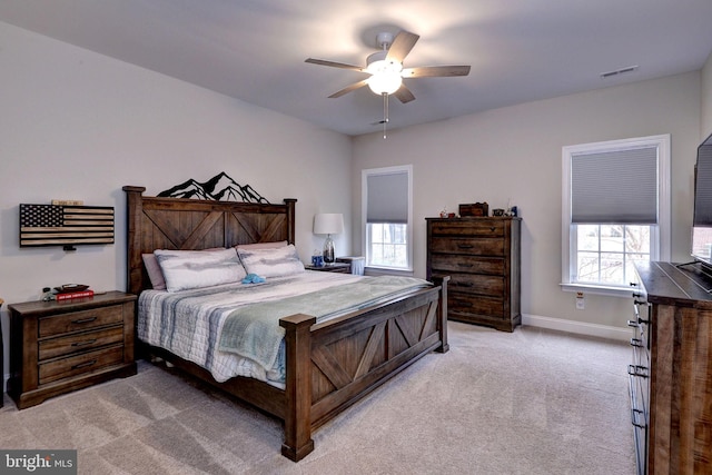 bedroom featuring visible vents, light colored carpet, baseboards, and ceiling fan