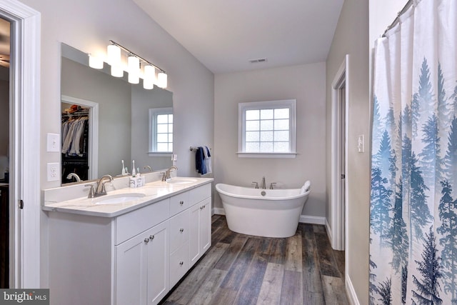 full bathroom featuring a sink, visible vents, a freestanding bath, and wood finished floors