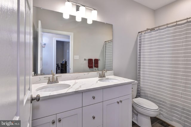 bathroom with a sink, toilet, and double vanity