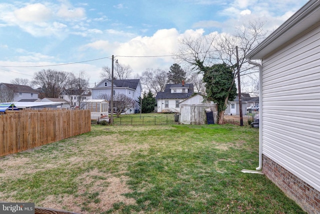 view of yard featuring an outdoor structure, a storage unit, fence, and a residential view