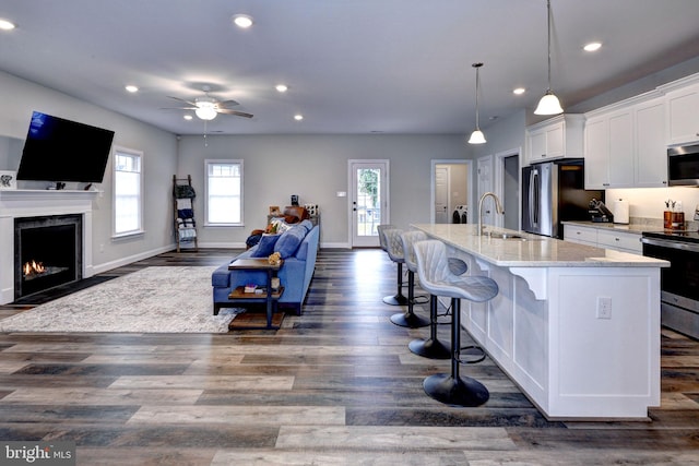 kitchen with recessed lighting, a sink, appliances with stainless steel finishes, white cabinetry, and open floor plan