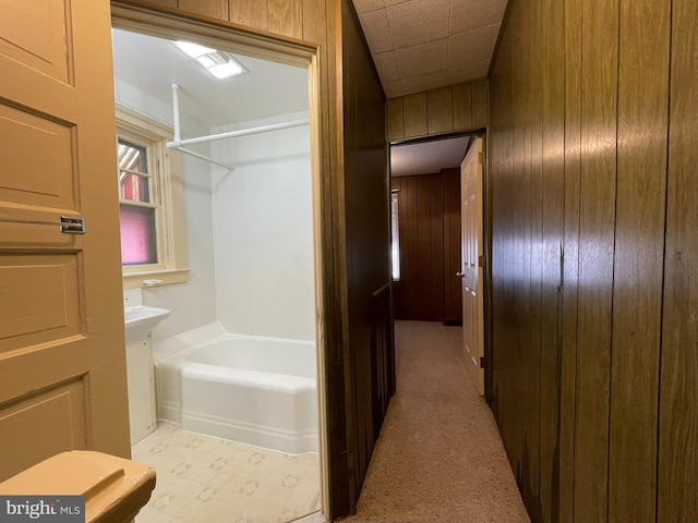 full bathroom featuring wood walls and washtub / shower combination