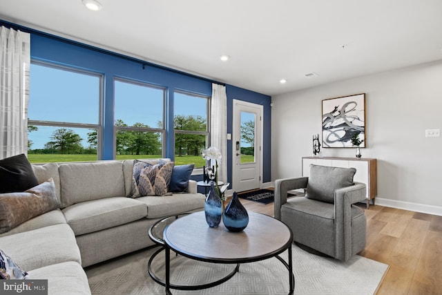 living room featuring baseboards, light wood-type flooring, a wealth of natural light, and recessed lighting