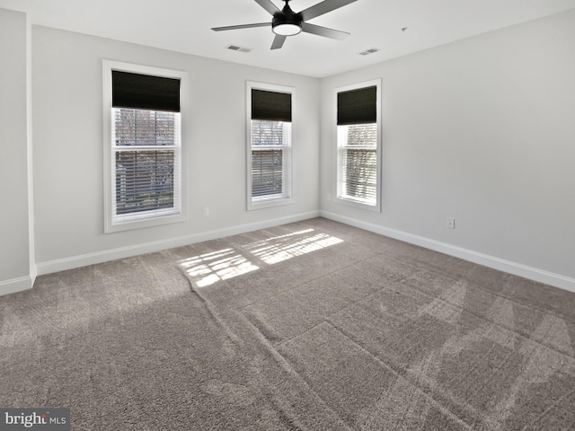 carpeted spare room with a ceiling fan, visible vents, and baseboards