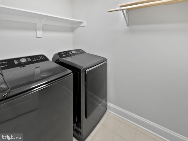 laundry area with laundry area, light tile patterned flooring, baseboards, and washing machine and clothes dryer