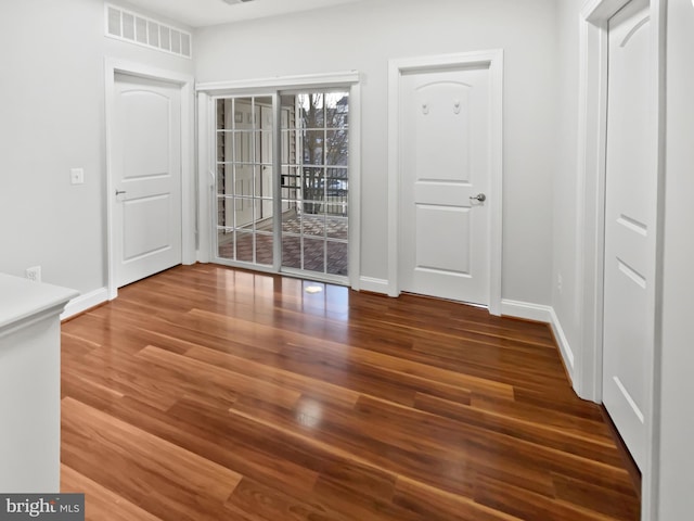 unfurnished dining area with baseboards, visible vents, and wood finished floors