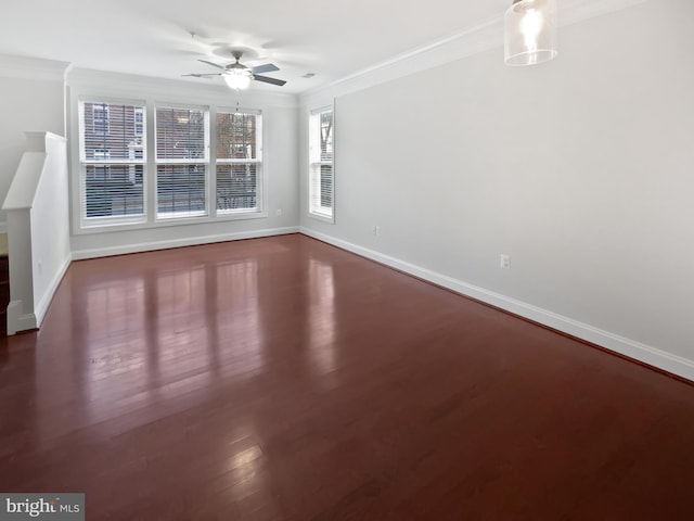 spare room with a ceiling fan, crown molding, baseboards, and wood finished floors