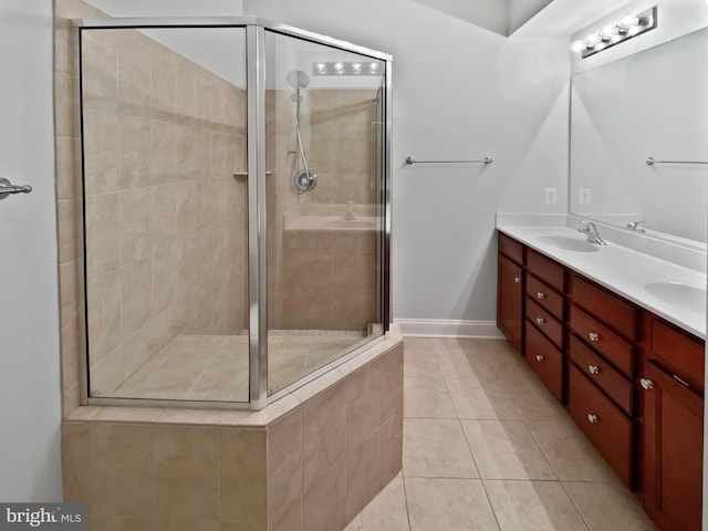 full bath featuring double vanity, a shower stall, a sink, and tile patterned floors