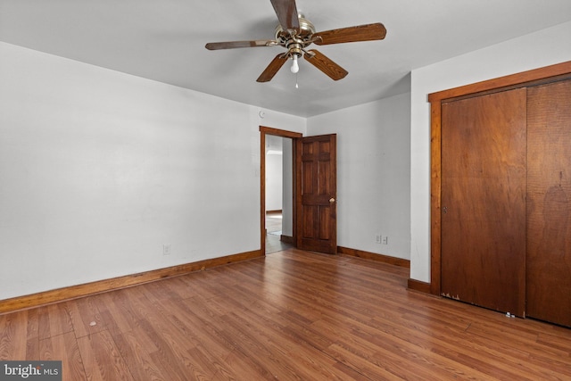 unfurnished bedroom with a closet, wood finished floors, a ceiling fan, and baseboards