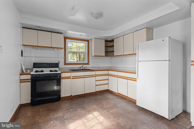 kitchen with tasteful backsplash, gas range, freestanding refrigerator, light countertops, and open shelves