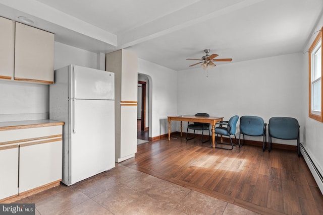 kitchen featuring arched walkways, wood finished floors, baseboards, baseboard heating, and freestanding refrigerator