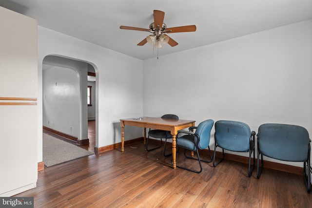 dining room featuring hardwood / wood-style flooring, baseboards, arched walkways, and a ceiling fan