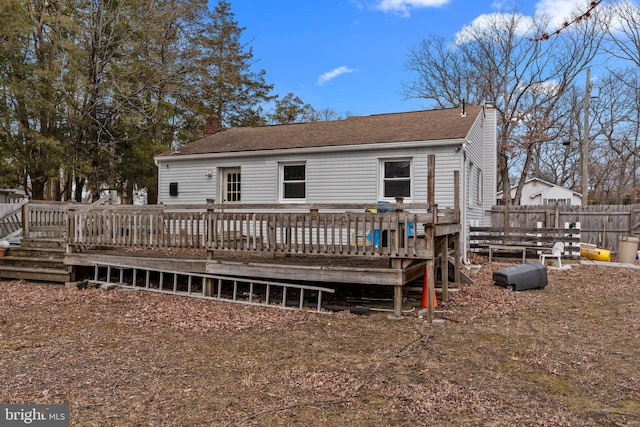 back of property featuring a chimney, fence, and a deck