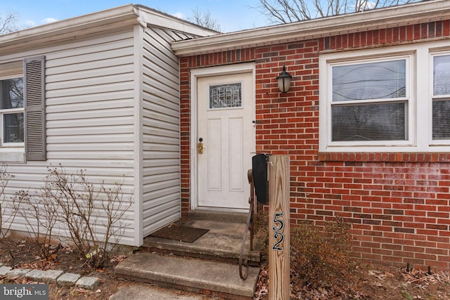 doorway to property featuring brick siding