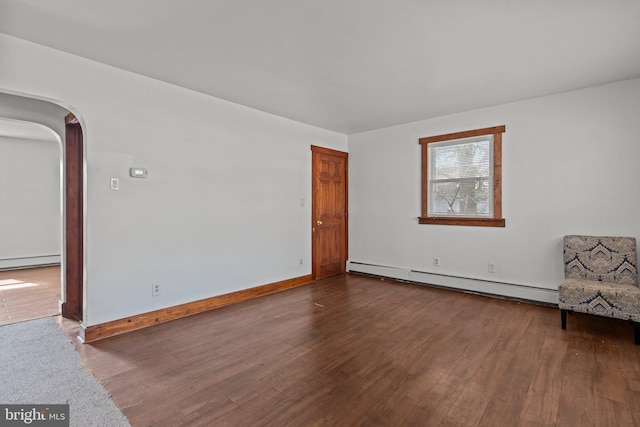 interior space with a baseboard heating unit, arched walkways, baseboards, and wood finished floors