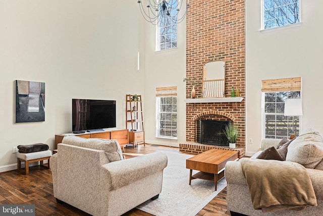 living area with baseboards, a high ceiling, dark wood finished floors, and a fireplace