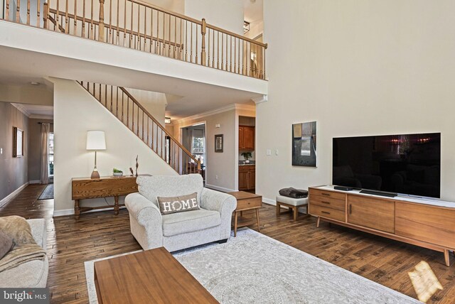 living room featuring stairs, baseboards, dark wood-style flooring, and crown molding