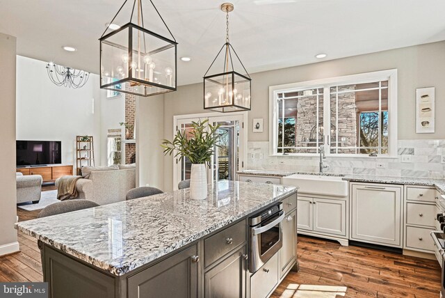 kitchen with a sink, light stone countertops, a healthy amount of sunlight, and wood finished floors