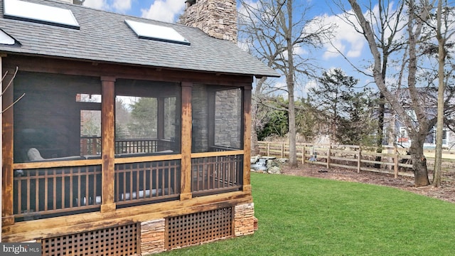 view of property exterior with stone siding, fence, a yard, a sunroom, and a chimney