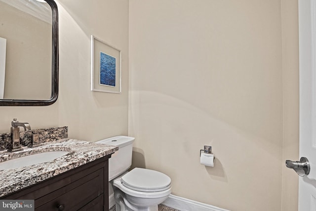 half bath featuring vanity, toilet, and baseboards