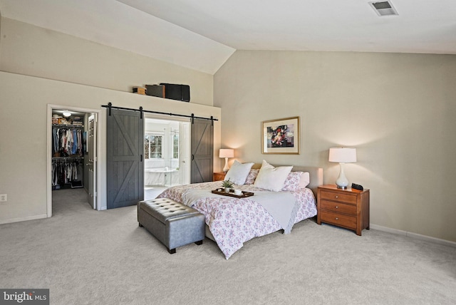 bedroom with a spacious closet, visible vents, carpet, and a barn door