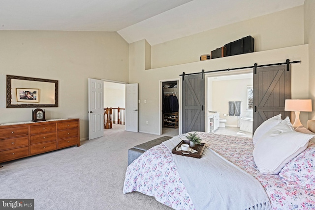 bedroom with a spacious closet, connected bathroom, a barn door, carpet floors, and a closet