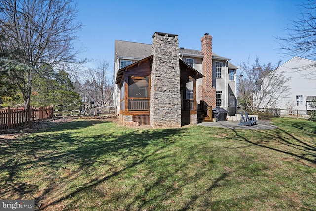 rear view of property featuring a patio area, fence, a lawn, and a chimney