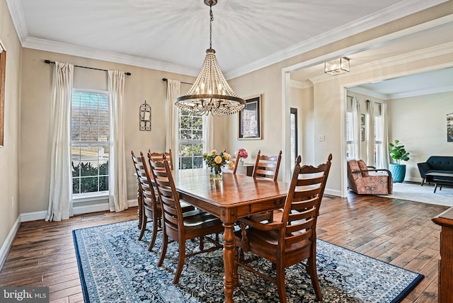 dining room featuring a chandelier, ornamental molding, baseboards, and hardwood / wood-style floors