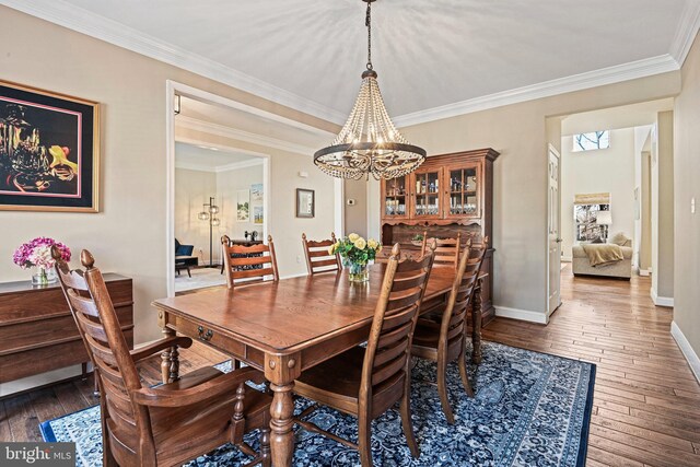 dining room with baseboards, a notable chandelier, hardwood / wood-style floors, and crown molding