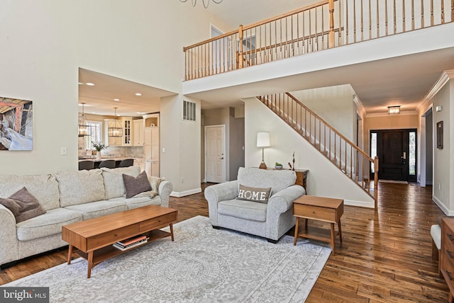 living room with stairway, baseboards, visible vents, hardwood / wood-style flooring, and crown molding