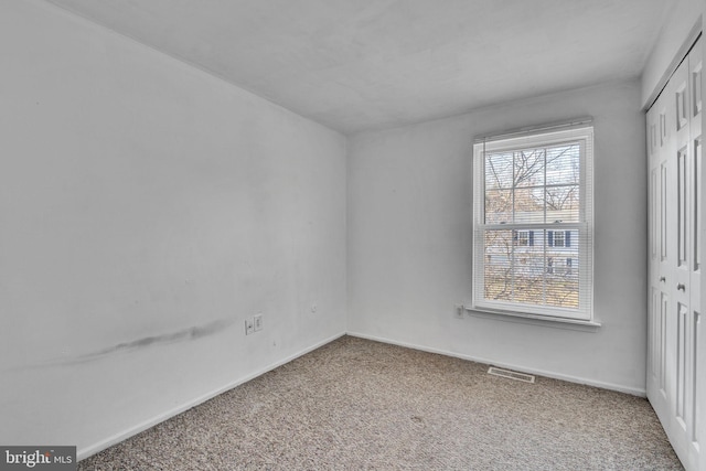 carpeted spare room featuring baseboards and visible vents