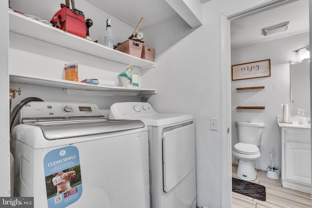 washroom featuring separate washer and dryer, wood finished floors, and laundry area