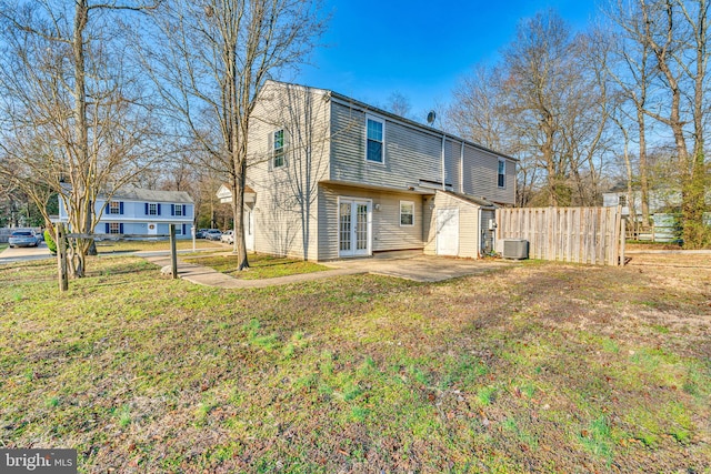 rear view of property with fence, central air condition unit, a lawn, french doors, and a patio