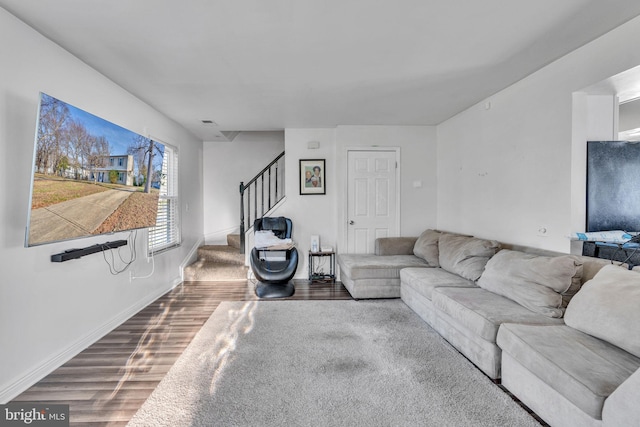 living area featuring stairway, baseboards, visible vents, and wood finished floors