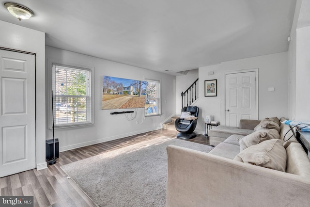 living room with stairway, baseboards, and wood finished floors