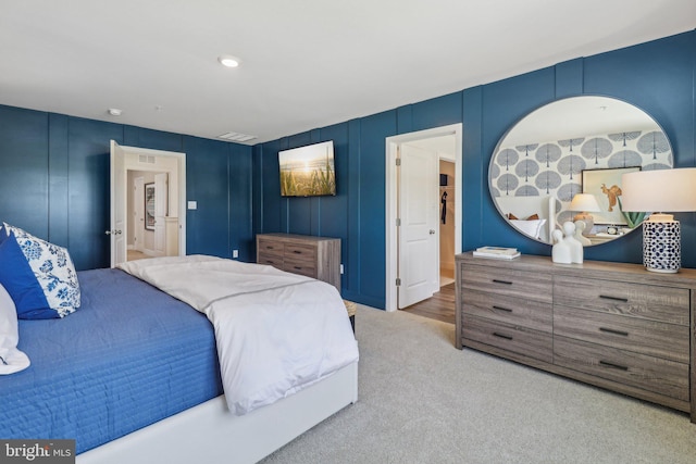 carpeted bedroom featuring visible vents and a decorative wall