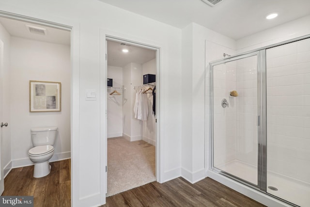 full bathroom with toilet, wood finished floors, visible vents, a shower stall, and a walk in closet