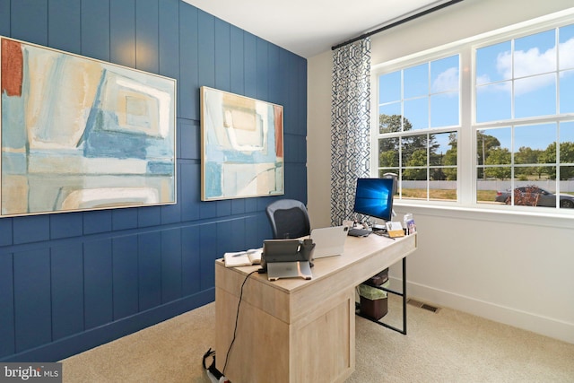 carpeted home office featuring visible vents, wooden walls, and baseboards