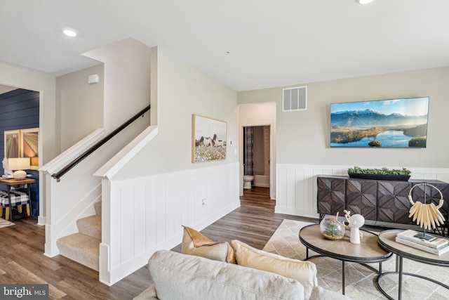 living room featuring a wainscoted wall, recessed lighting, visible vents, wood finished floors, and stairs