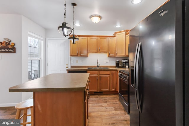 kitchen with light wood-style floors, range with gas stovetop, a sink, and black fridge with ice dispenser