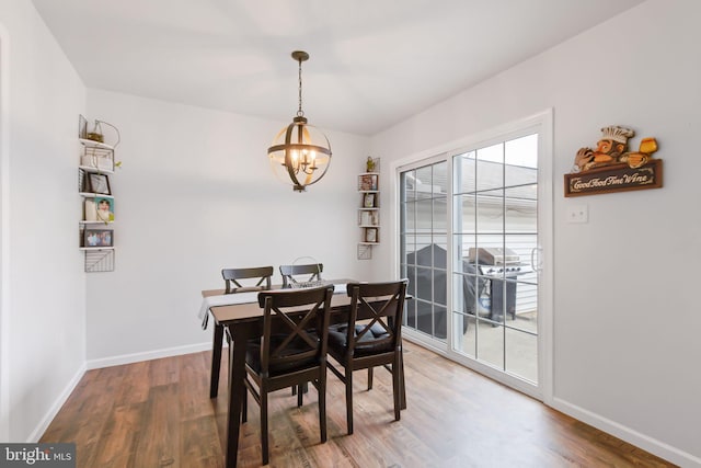 dining room with a chandelier, wood finished floors, and baseboards