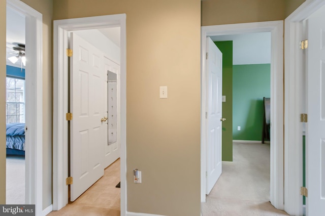 hallway featuring light carpet and baseboards