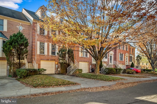 townhome / multi-family property featuring concrete driveway, brick siding, stairs, and a garage