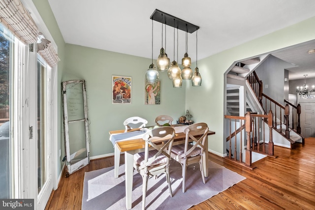 dining space with stairway, baseboards, wood finished floors, and a notable chandelier