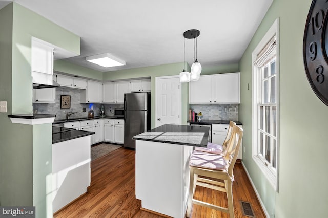 kitchen with dark countertops, appliances with stainless steel finishes, white cabinets, and dark wood-style flooring