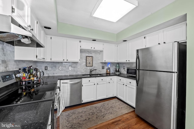 kitchen with dark wood-style flooring, appliances with stainless steel finishes, a sink, white cabinets, and under cabinet range hood