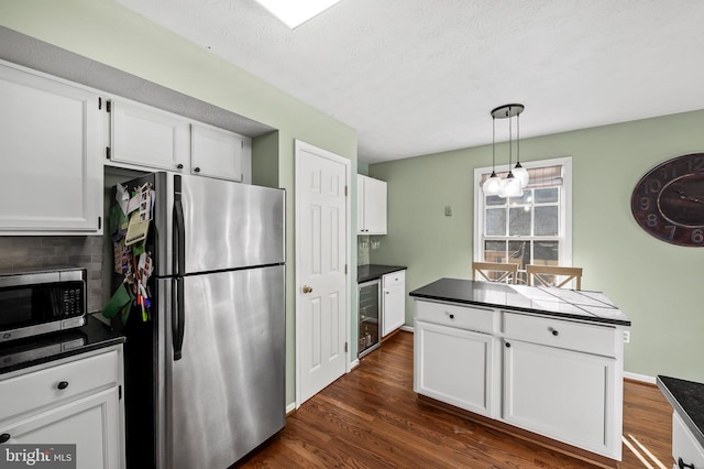 kitchen featuring white cabinets, stainless steel appliances, dark countertops, and wine cooler