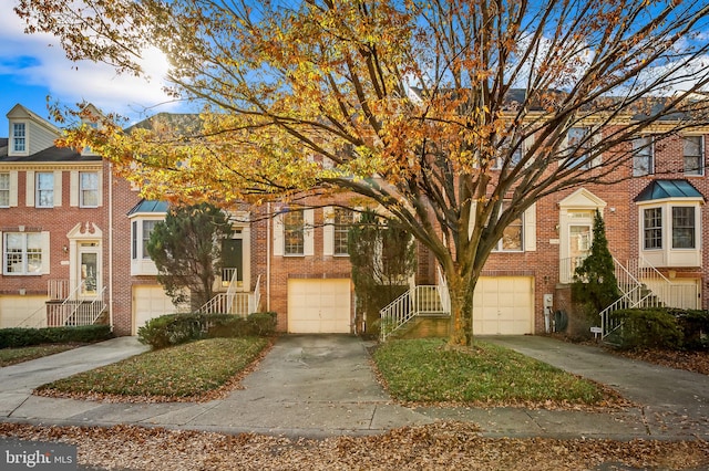 view of property with brick siding, an attached garage, and driveway